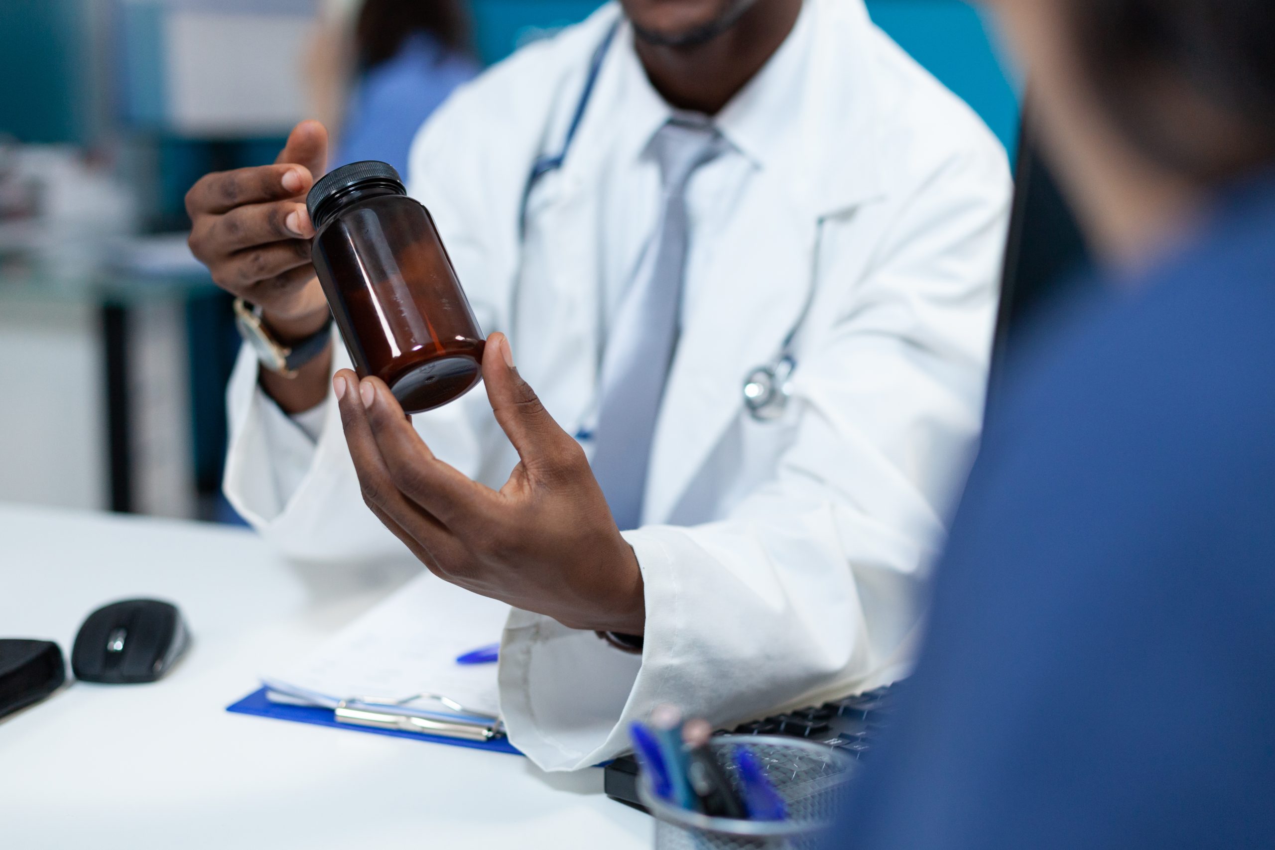 Closeup of african american pediatrician doctor holding pills bottle