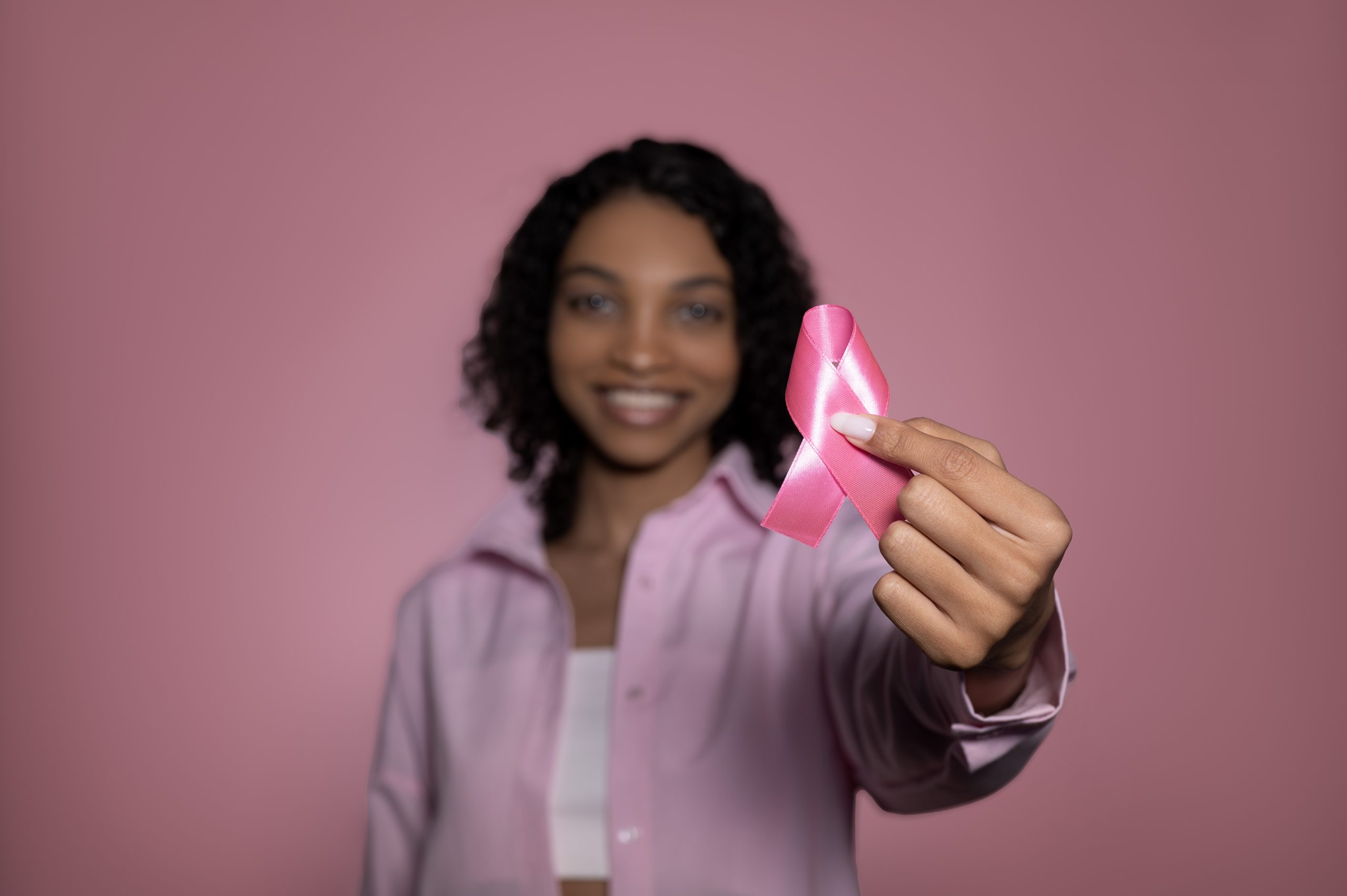 Cute smiling balck girl holding pink ribbon. Breast cancer awareness month