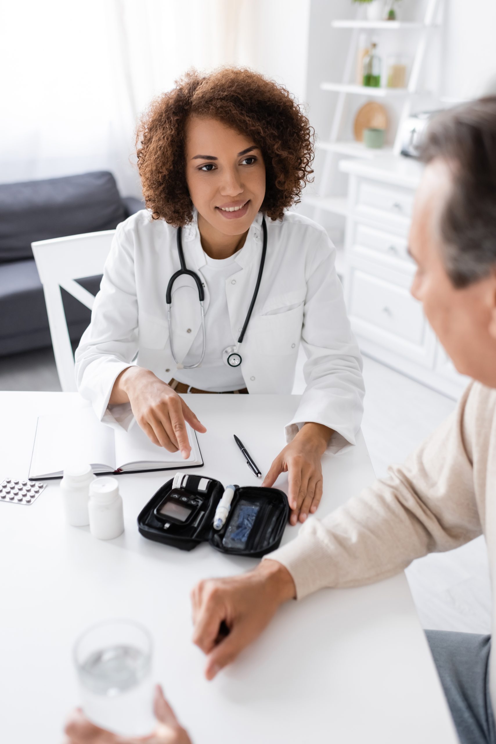 smiling african american doctor looking at middle aged man with diabetes